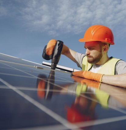 Male worker with solar batteries. Man in a protective helmet. Installing stand-alone solar panel system.